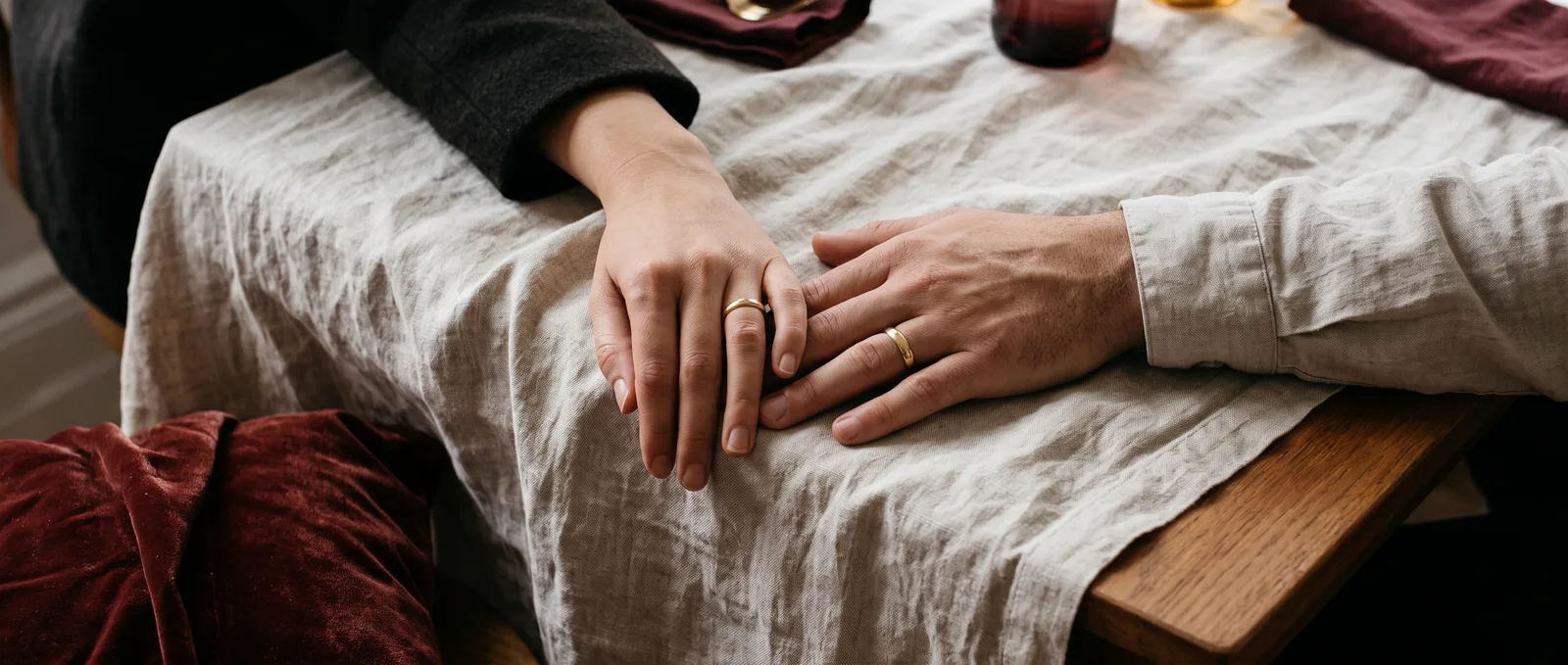 Two hands resting together, each wearing a gold wedding band
