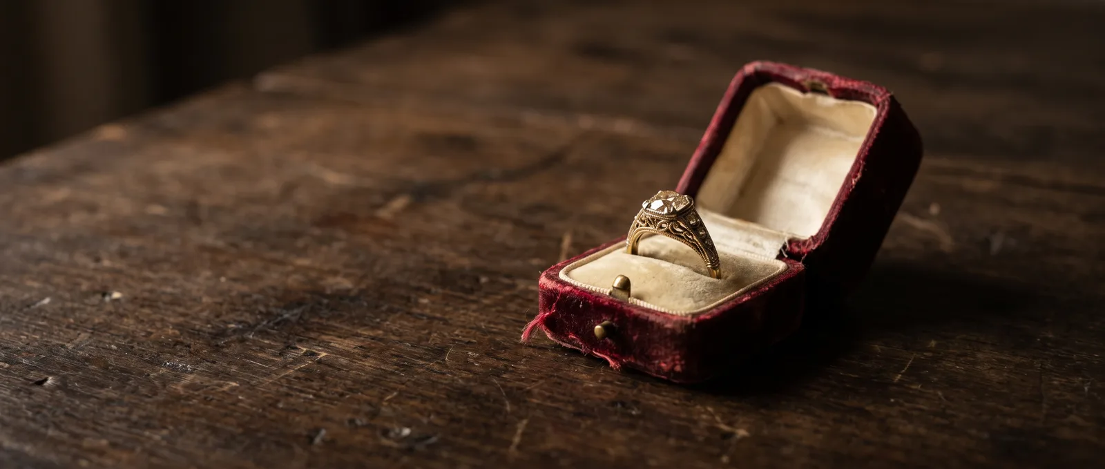An antique gold ring with an old-mine cut diamond in a worn velvet box