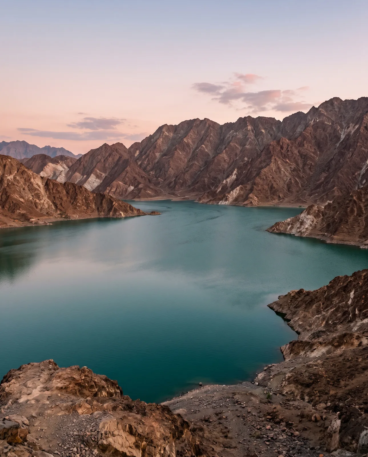 The Hatta dam lake between bare mountains at dusk
