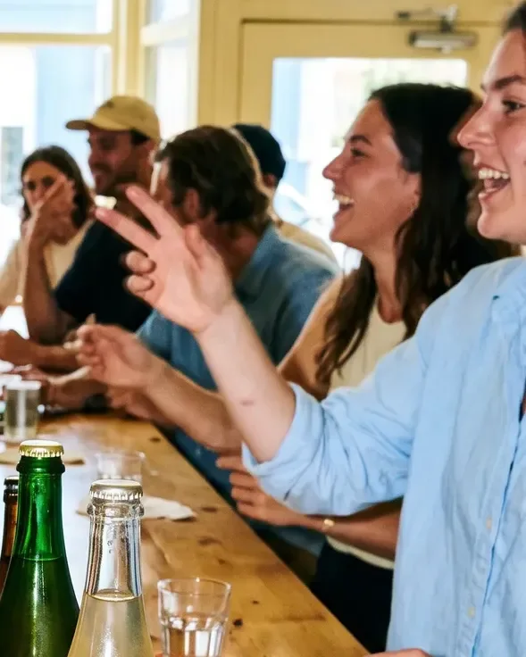 Customers laughing along a long wooden tasting counter