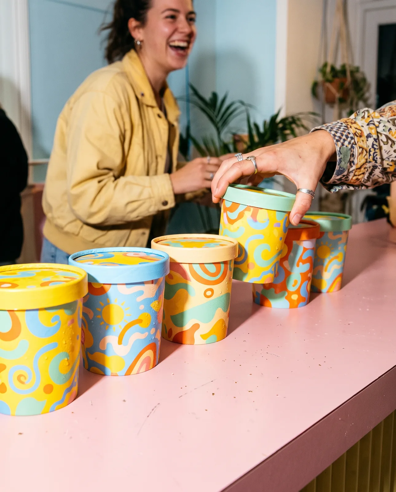 Sundae Club ice cream tubs in bright colours lined up on a pink counter