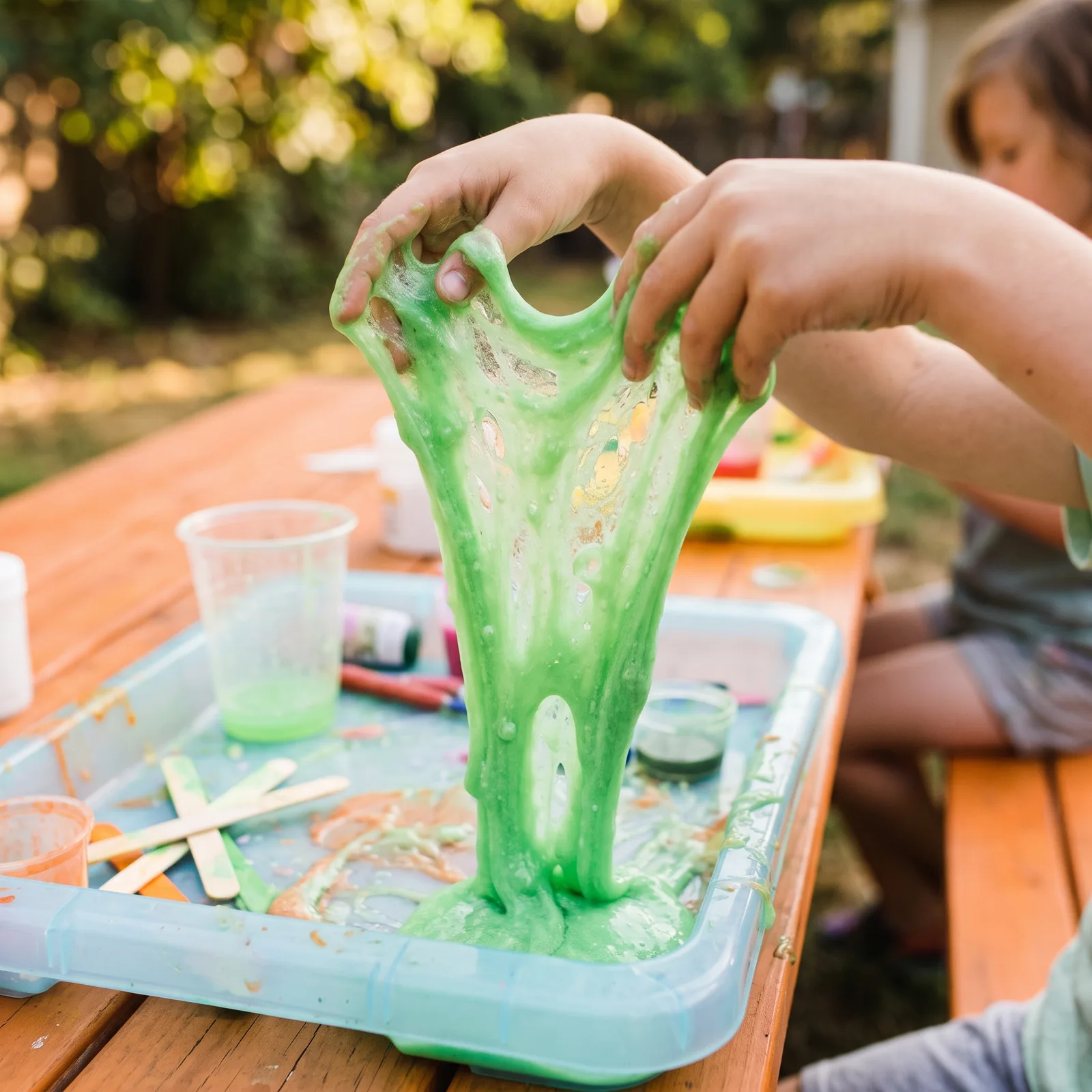 Child stretching bright green slime
